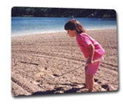 Young blind child exploring the beach with her cane
